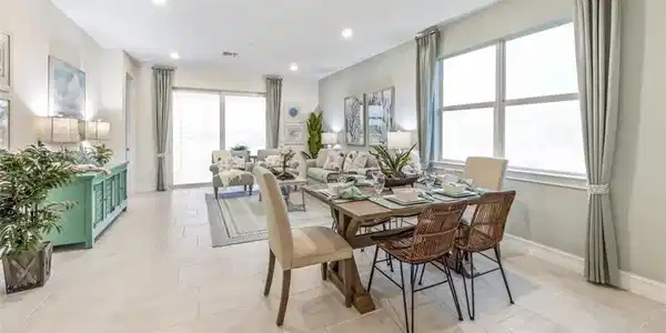 Image 4: Expansive open-concept living area featuring large format tile flooring, a dining space with a rustic wood-finish table, and a living room with sliding glass doors
