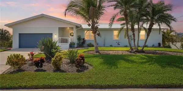 Image 2: Ranch-style house with a garage, driveway, stucco siding, a porch, and a lawn - Virtually Edited Image