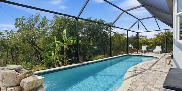 Image 3: Outdoor pool with a sunroom, a patio, and glass enclosure - Virtually Edited Image