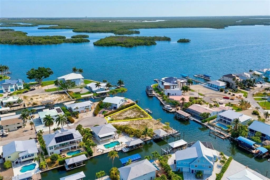 Image 2: Waterfront property featuring direct canal access, an undeveloped lot, and surrounding residential structures - Virtually Edited Image