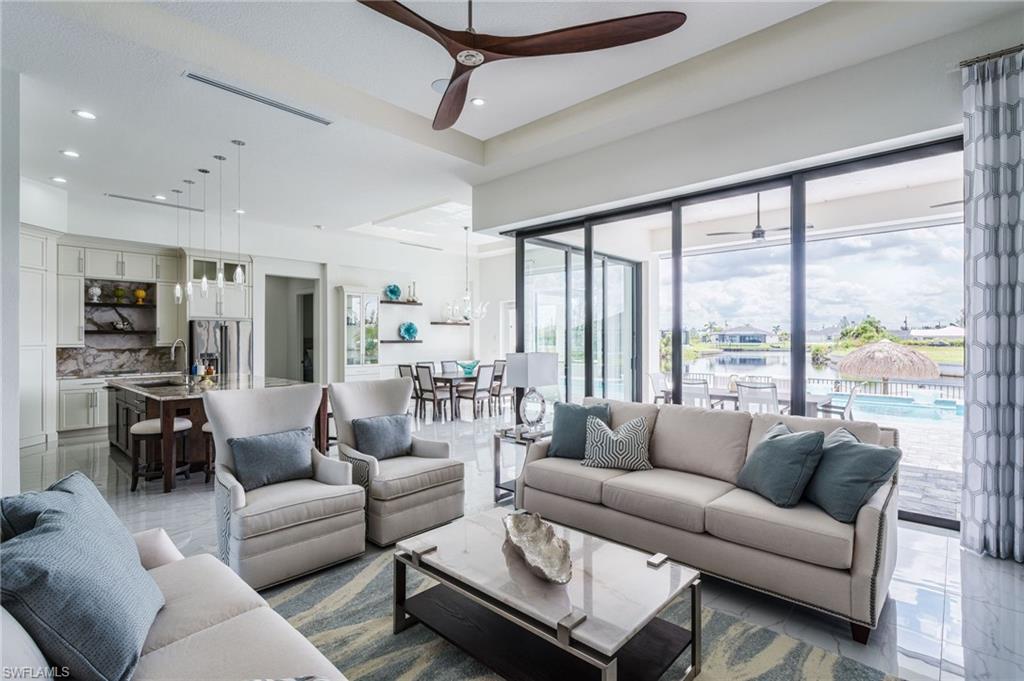 Image 4: Open-concept living area with large format tile flooring, a dark wood-finish ceiling fan, and recessed lighting