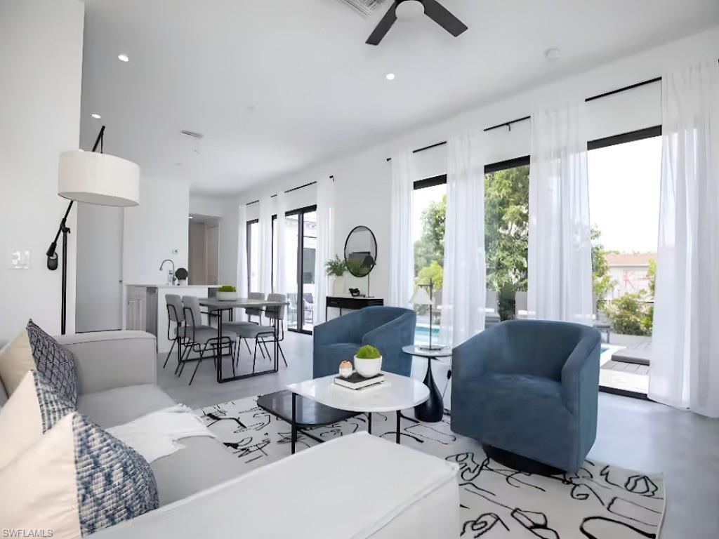 Image 2: Open-concept living space featuring high ceilings, recessed lighting, and expansive floor-to-ceiling windows with sliding glass door access to the pool
