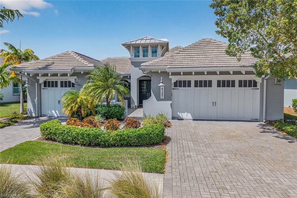 Image 2: Beautiful coastal elevation with three-car garage and inviting front courtyard entrance.