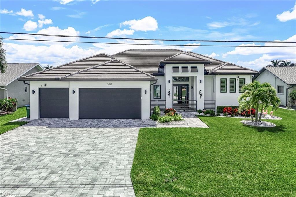 Image 2: View of front of house with a front yard, stucco siding, and decorative driveway