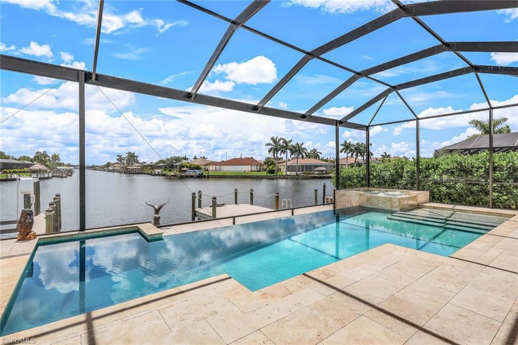 Image 3: View of pool with a sunroom, a water view, a pool with connected hot tub, a lanai, and a patio area