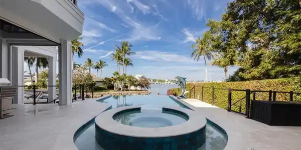 Image 3: View of swimming pool featuring a patio area, a pool with connected hot tub, and a water view