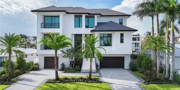 Image 2: Modern architectural exterior featuring a white stucco finish and a dark tile roof