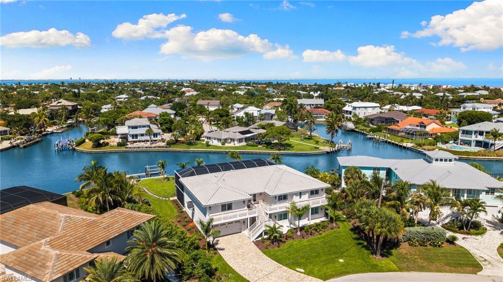 Image 2: Waterfront property featuring a private boat dock, lush tropical landscaping, and a paver driveway
