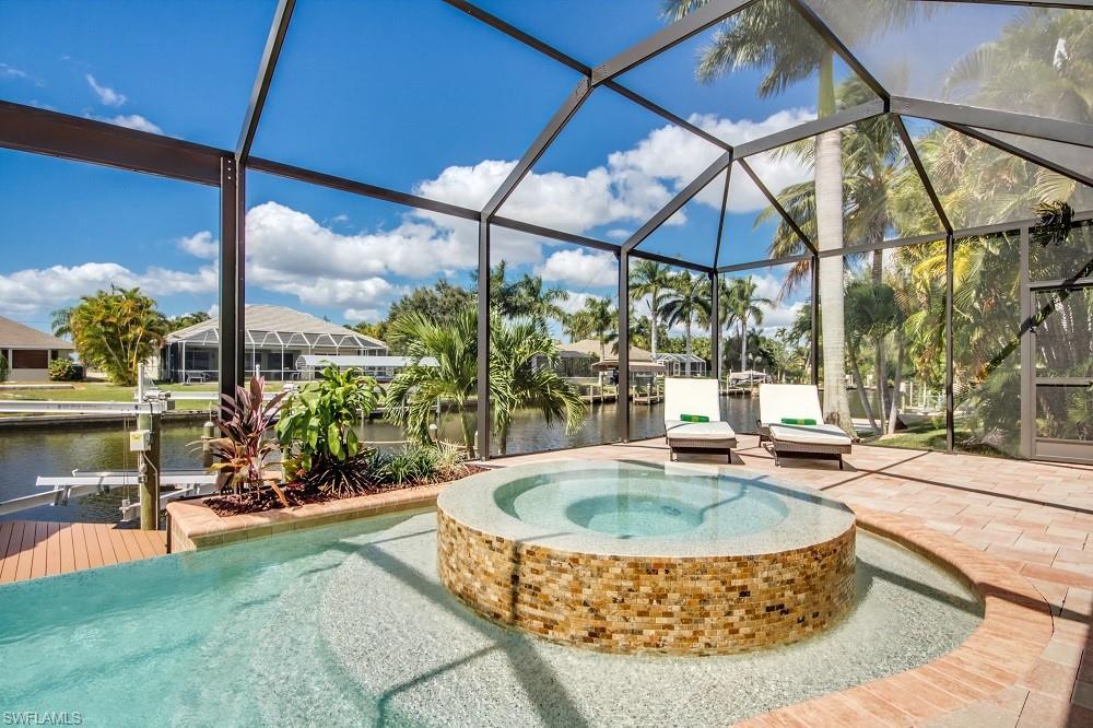 Image 2: View of pool featuring a water view, a sunroom, a lanai, a patio, and a pool with connected hot tub