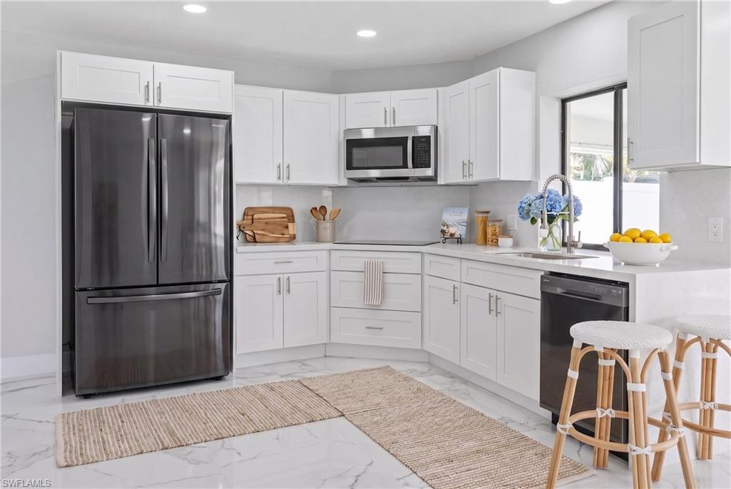 Image 3: White shaker cabinetry, stainless steel appliances, and light countertops define this kitchen space