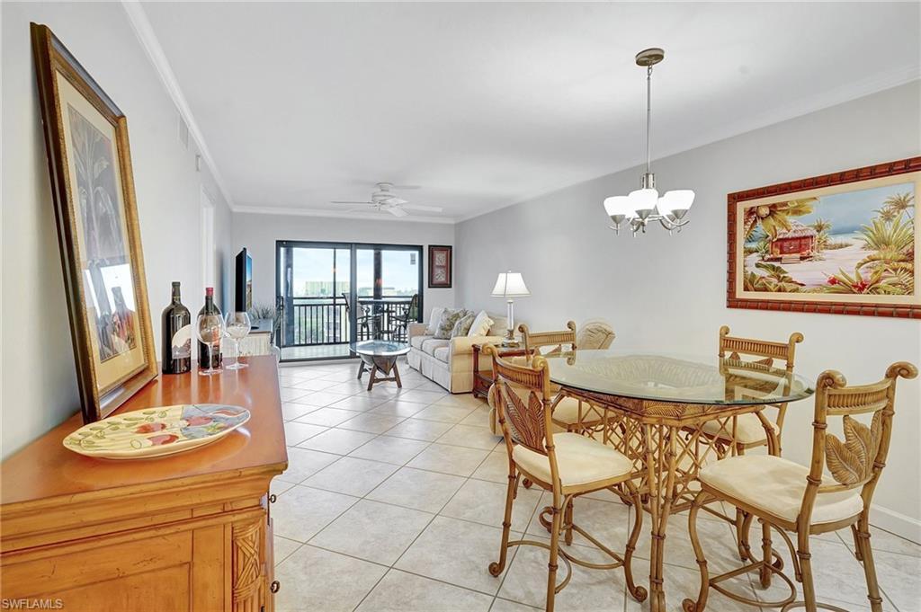 Image 4: Dining space featuring ornamental molding, light tile patterned floors, a ceiling fan, and a chandelier