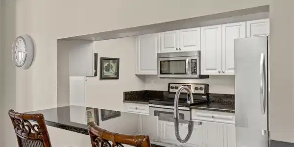 Image 2: Kitchen featuring white cabinets, dark stone countertops, appliances with stainless steel finishes, and sink