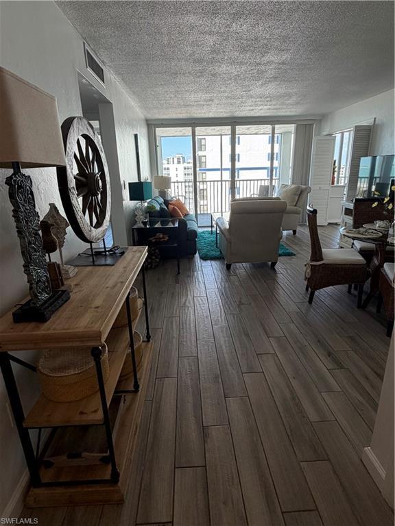 Image 4: Living room with healthy amount of natural light, dark wood finished floors, a textured ceiling, and expansive windows