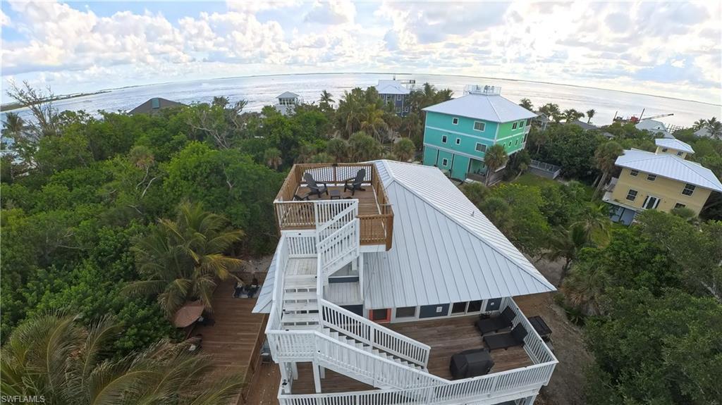 Image 4: Coastal property featuring multiple outdoor deck spaces, a rooftop deck with seating, and a metal roof