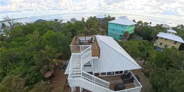 Image 4: Coastal property featuring multiple outdoor deck spaces, a rooftop deck with seating, and a metal roof