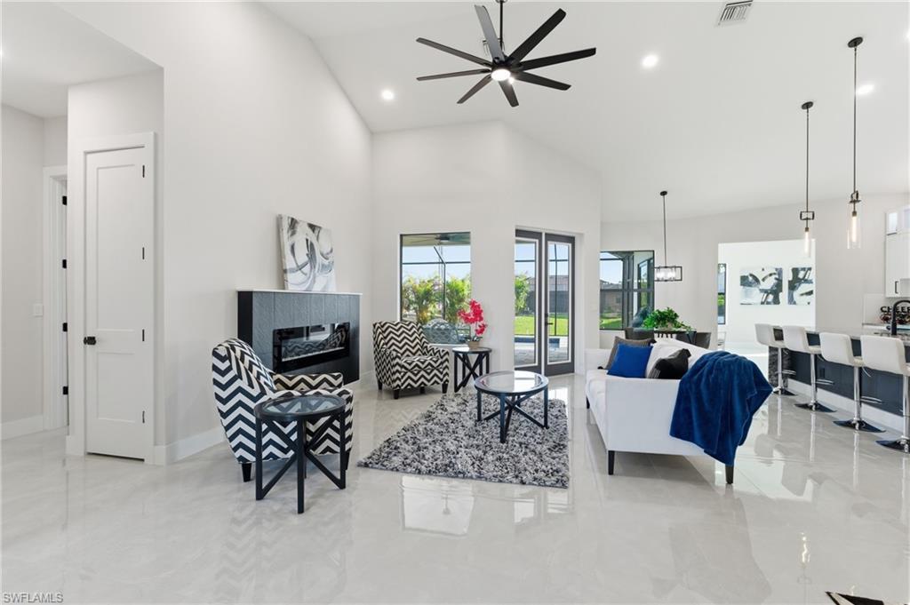 Image 4: Living area featuring ceiling fan, recessed lighting, a tile fireplace, and vaulted ceiling
