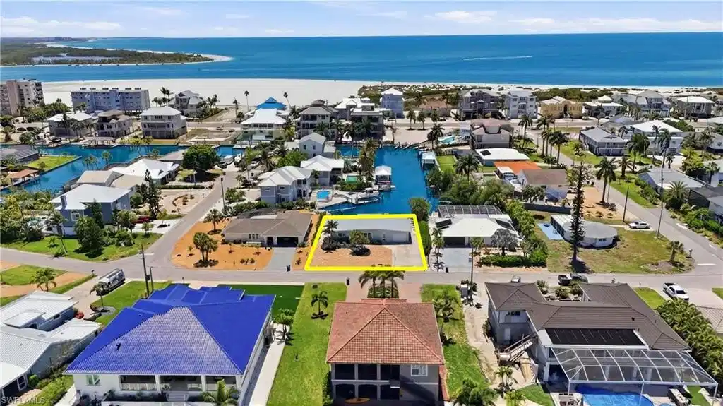 Image 1: Aerial view of the property, showcasing its location near canals and a large body of water, with a beach visible in the distance - Virtually Edited Image