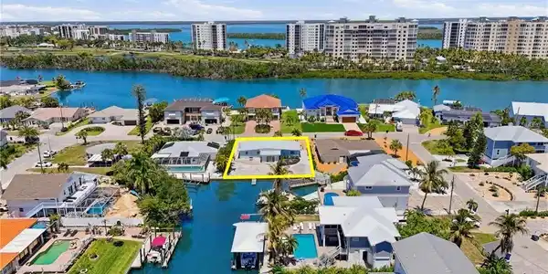Image 2: Waterfront property featuring a private boat dock, a paved driveway, and mature landscaping - Virtually Edited Image