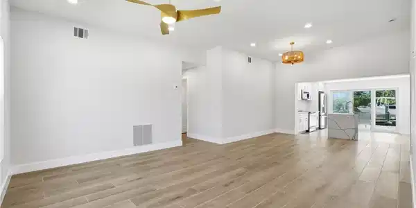 Image 3: Spacious interior featuring a contemporary ceiling fan, recessed lighting, and light-toned tile flooring - Virtually Edited Image