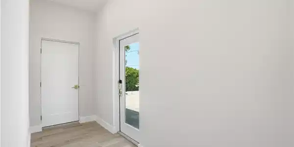 Image 4: Entryway with light-colored tile flooring, white walls, and a recessed ceiling light - Virtually Edited Image