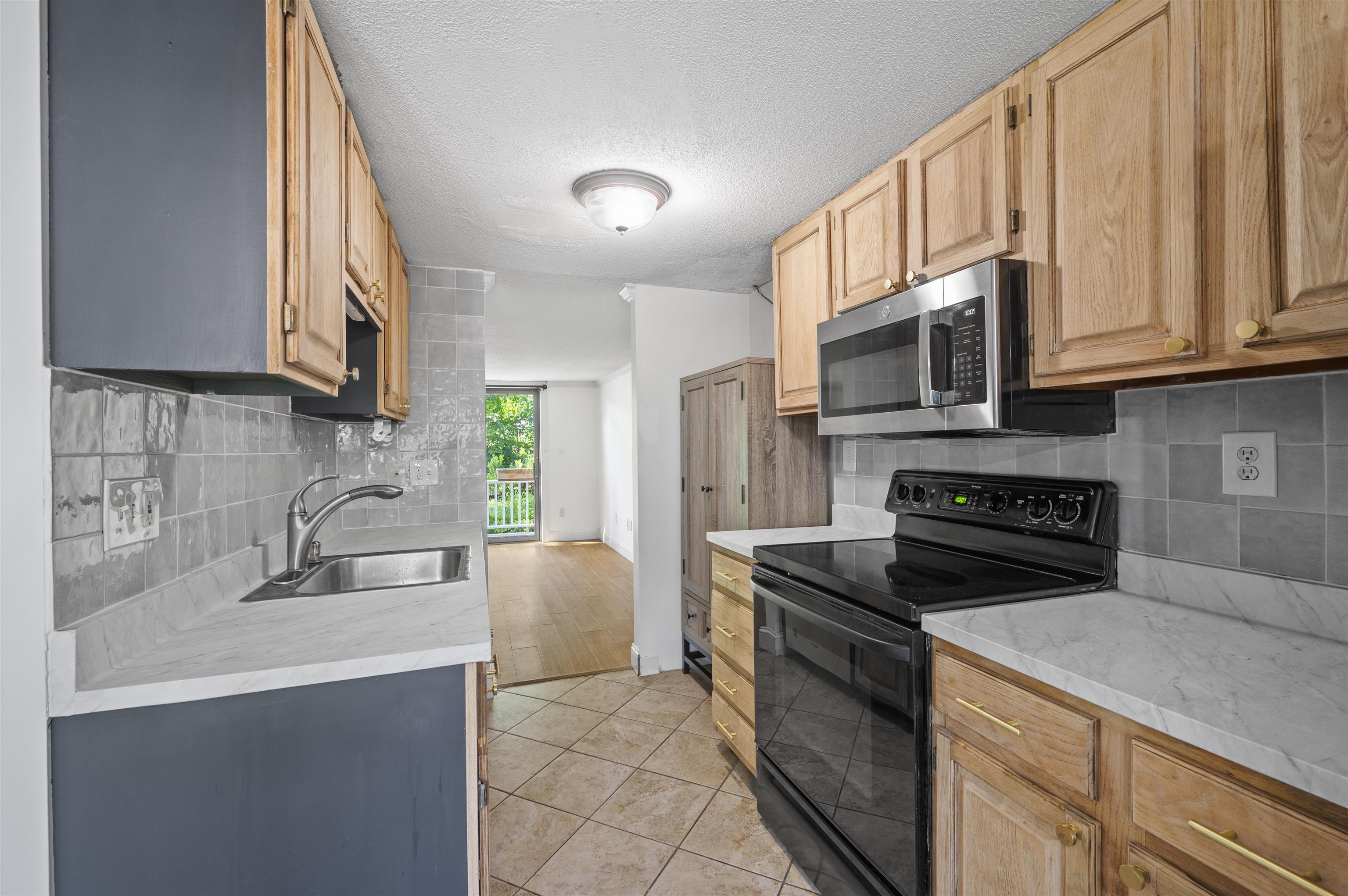 Image 4: Galley kitchen with oak cabinets & stainless steel appliance Image 4: Galley kitchen with oak cabinets & stainless steel appliance