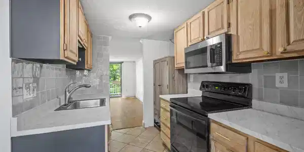 Image 4: Galley kitchen with oak cabinets & stainless steel appliance Image 4: Galley kitchen with oak cabinets & stainless steel appliance