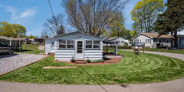 Image 2: Lovely corner lot, one of the largest in the complex. Grass enhanced. Extended roofline over deck destroyed by July 4th storm.
