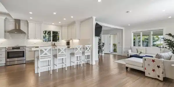 Image 4Living Room: Entryway opens to an airy open-concept interior filled with natural light. Beautiful wood flooring, crown molding, and recessed lighting create a warm yet refined atmosphere, while a striking palladium window serves as a stunning focal point.