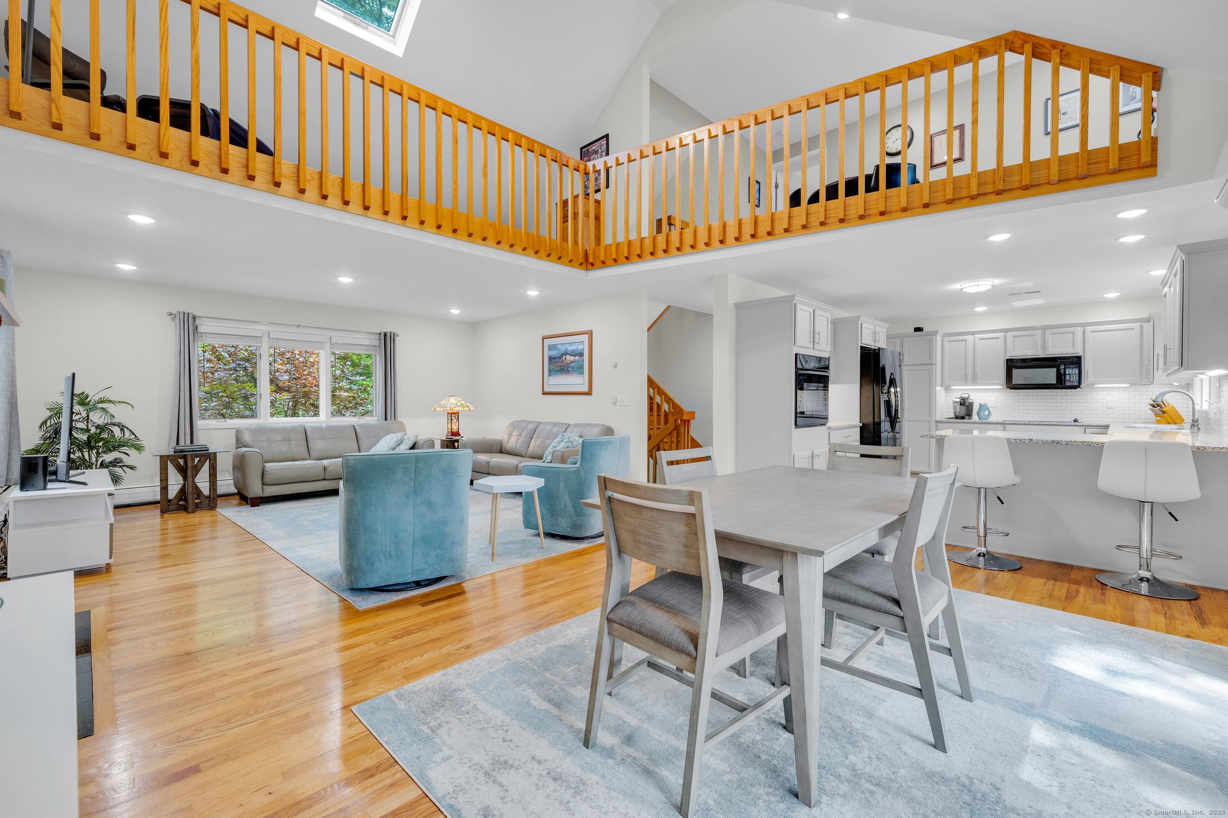 Image 4Living Room: Open concept floor plan, soaring cathedral ceiling, light-filled interior spaces, and hardwood flooring in the living/dining room, and kitchen.