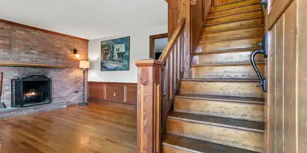 Image 4: The custom wainscoting and warm brick fireplace elevate this classic 1930's home