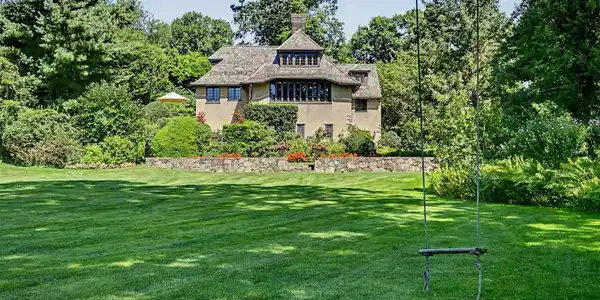 Image 2: Expansive lawn and beautifully landscaped gardens create a picturesque approach to the home, highlighted by a charming tree swing