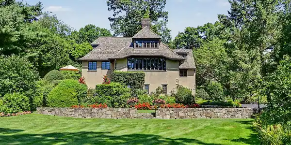 Image 3: Front of the house with stunning gardens, stone walls and carefully curated trees and bushes