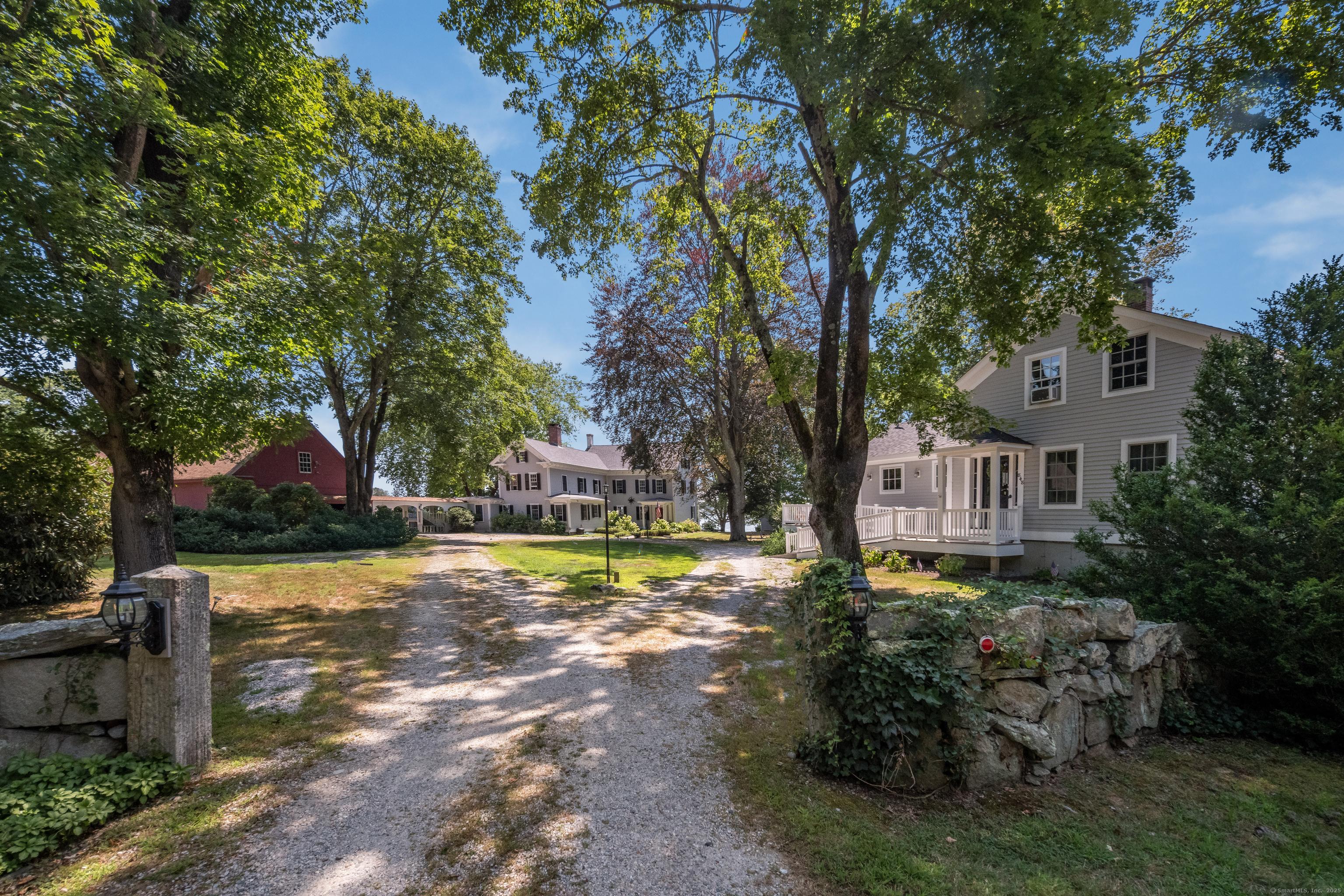Image 1Back of House: The private driveway gracefully winds to the main residence's back entrance, offering convenient barn/garage access while showcasing the property's mature, professionally landscaped grounds.