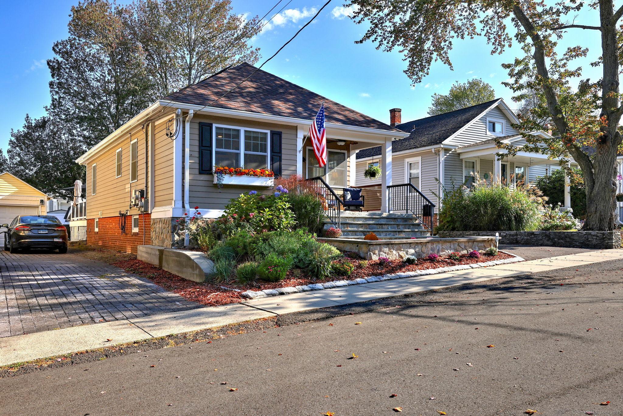 Image 4: Newer sidewalk, stone facing on wall & front/side/back of home. There are 4 water spigots - Notice you can set up an outside shower on driveway side with the hot water spigot, too! No Grass! Driveway a year old.