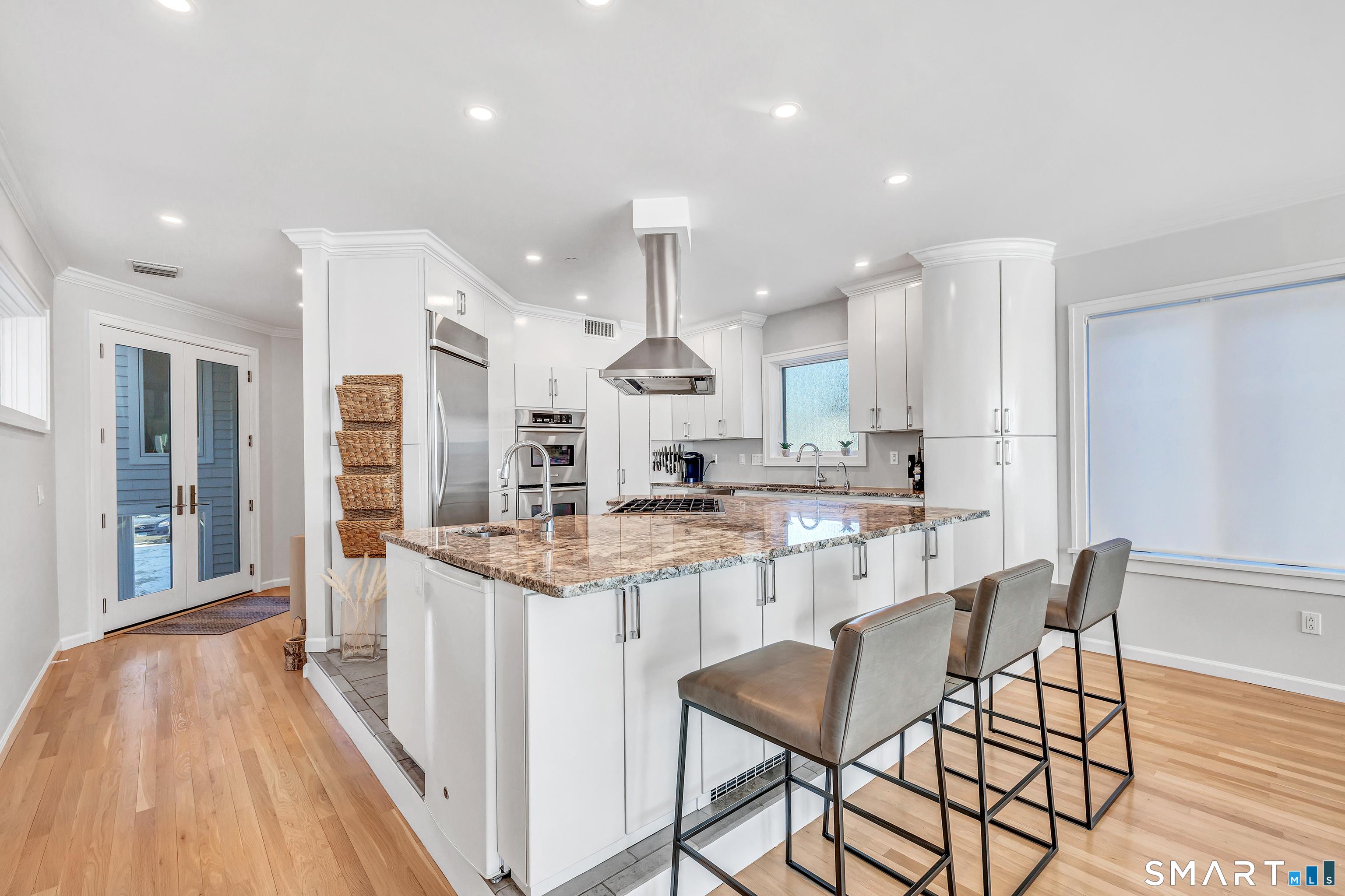Image 4Kitchen: Sun-filled custom wood kitchen with recently upgraded cabinet hardware, 6-burner pro-grade cooktop, and Bosch dishwasher. Large center island with 3-person breakfast bar. Note the double-door entry to the large walk-in pantry/laundry at the right corner.