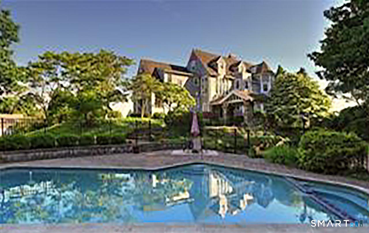 Image 2: A serene backyard retreat featuring a heated gunite pool surrounded by lush landscaping, with the historic estate rising gracefully above perfect for summer relaxation and outdoor entertaining.