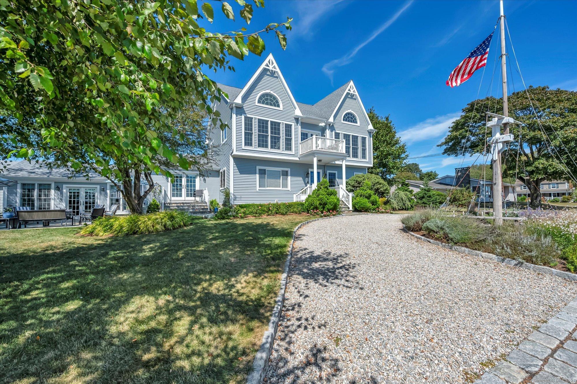 Image 3Front Yard: Classic New England charm meets coastal elegance in this beautifully landscaped home, featuring a nautical flagpole, curved gravel driveway, and inviting outdoor spaces just steps from the marina.