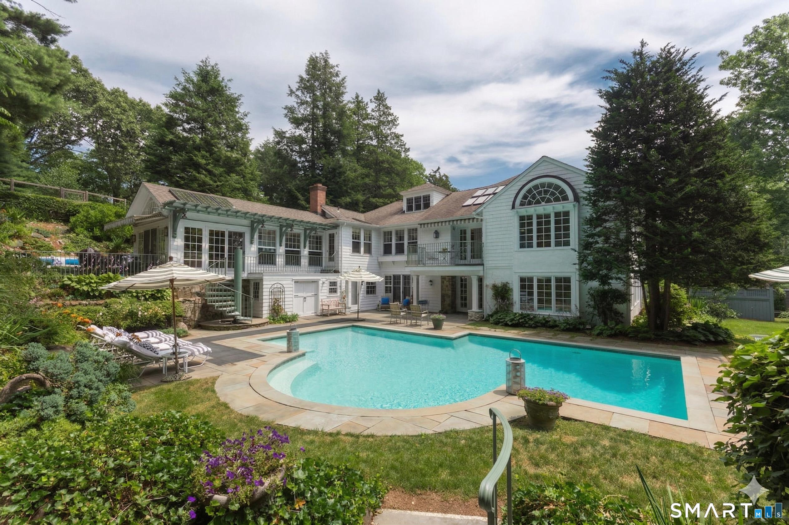 Image 1Back Yard: Stunning resort-style backyard featuring a sparkling heated gunite pool, spa, lush landscaping, and expansive patio - perfect for outdoor entertaining in Darien, CT.